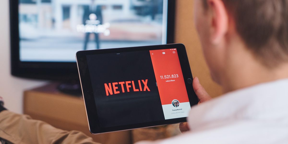 egy férfi egy tabletet tart a kezében, amin a Netflix oldala van megnyitva