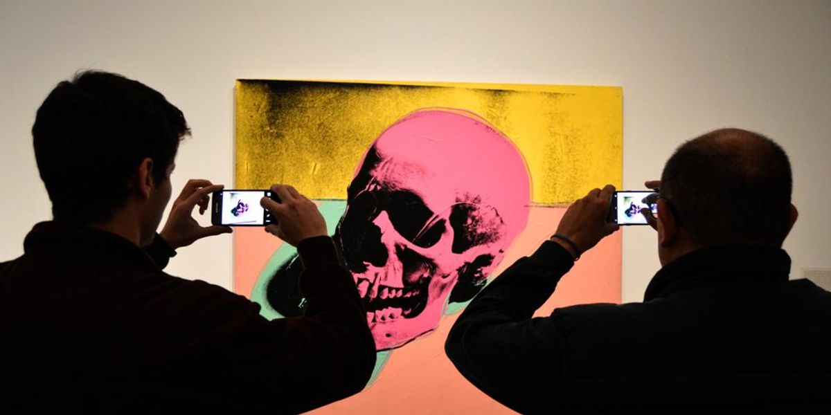 Egy koponyát ábrázoló Warhol-festményt fényképeznek