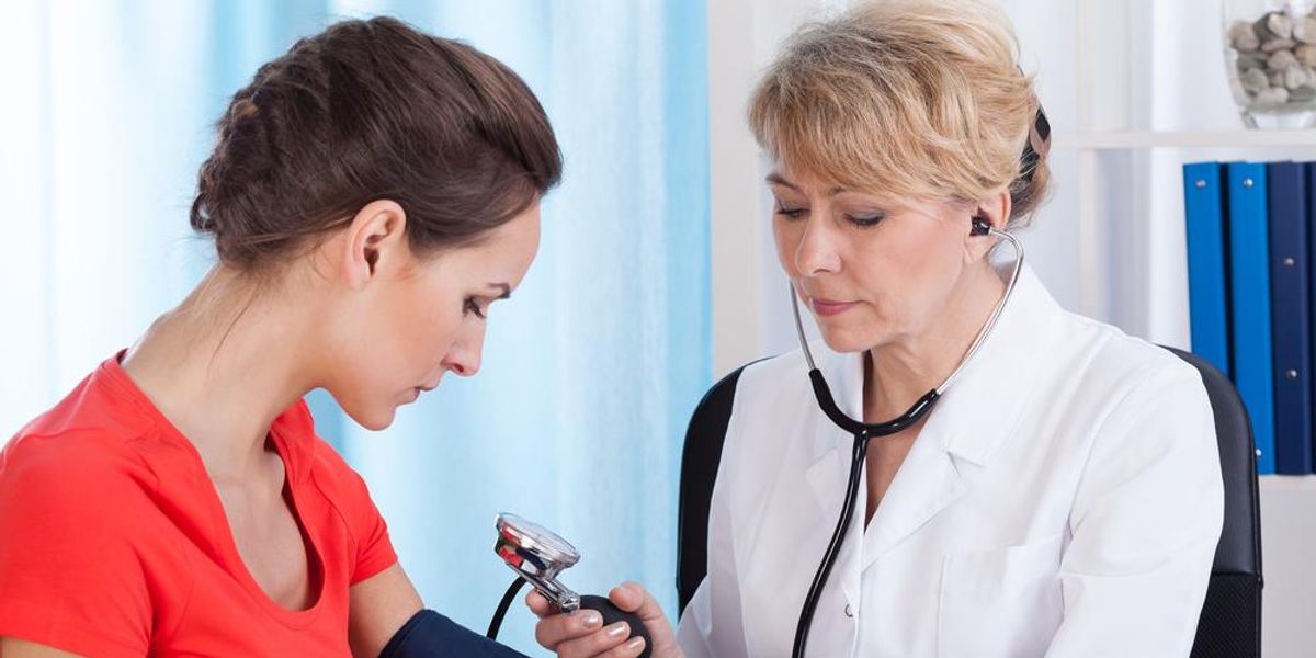 Orvos női beteg vérnyomását méri