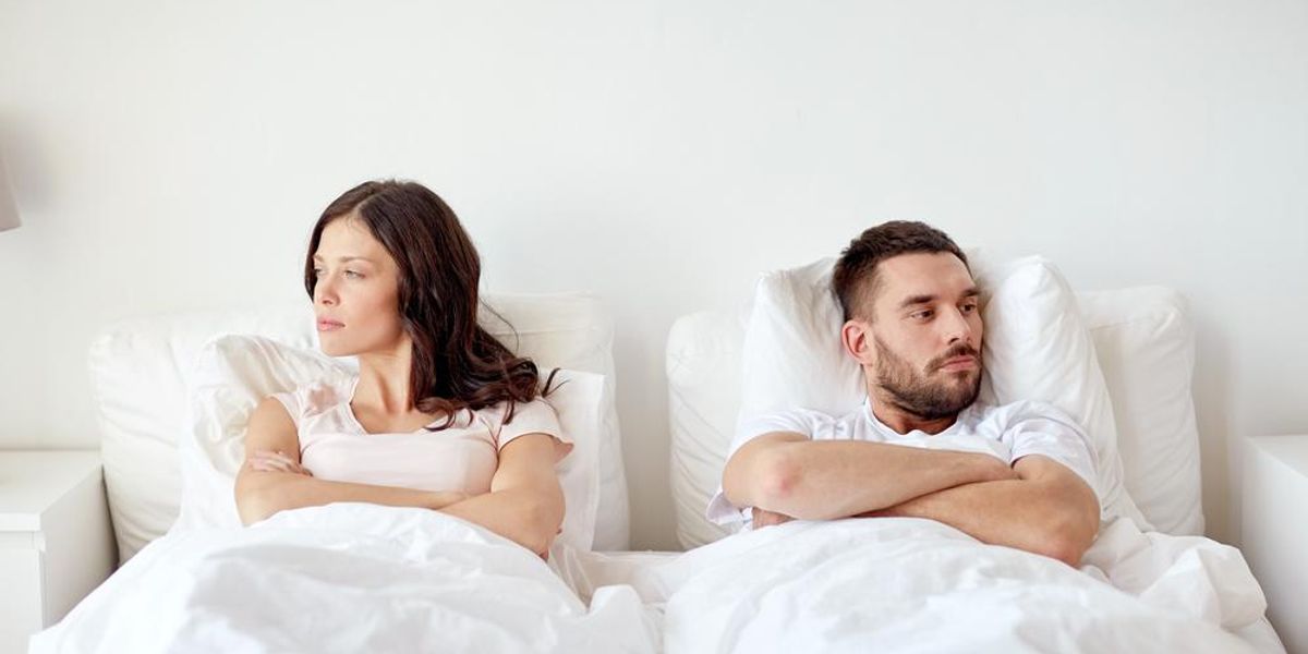 Egy nő és egy férfi fehér ágyneműben fekszik az ágyban