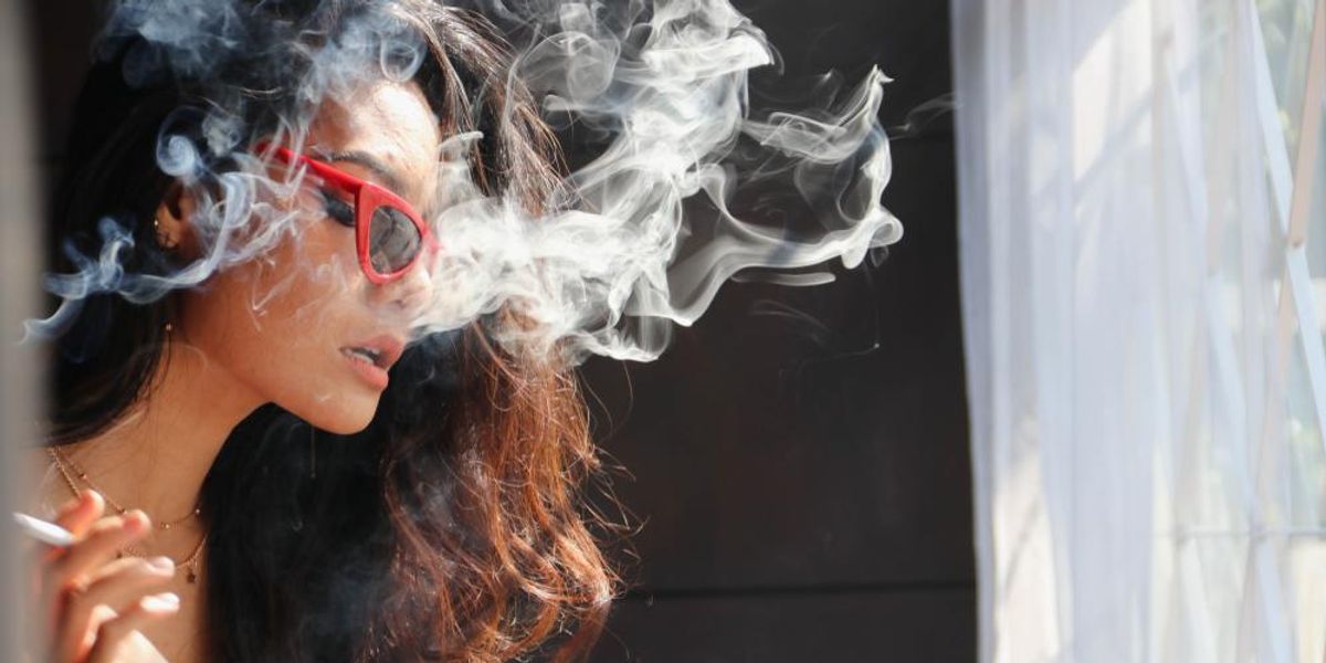 Fiatal nő dohányzik, füst lengi körül