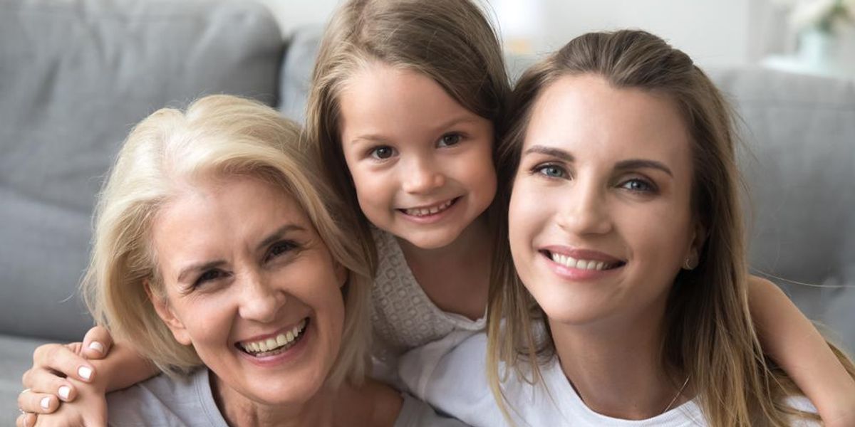 Három női generáció: nagymama, anya és lánya mosolyogva néz a kamerába