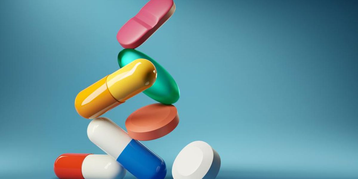 Gyógyszer tabletták és antibiotikumok egymás tetején, kék háttér előtt