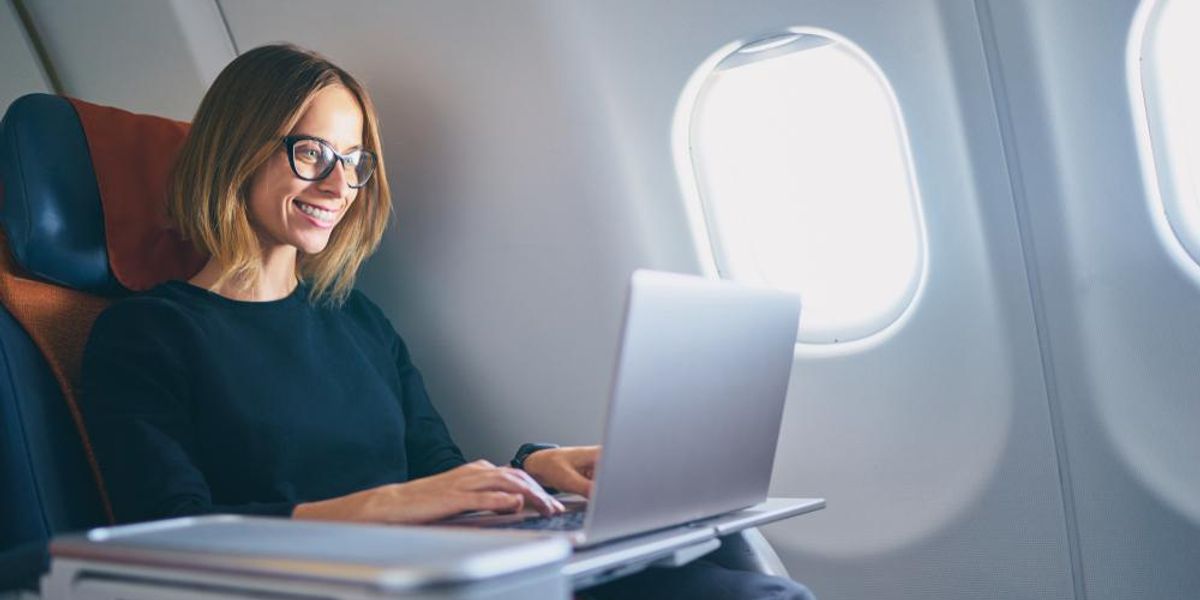 Fiatal nő laptopozik a repülőgépen