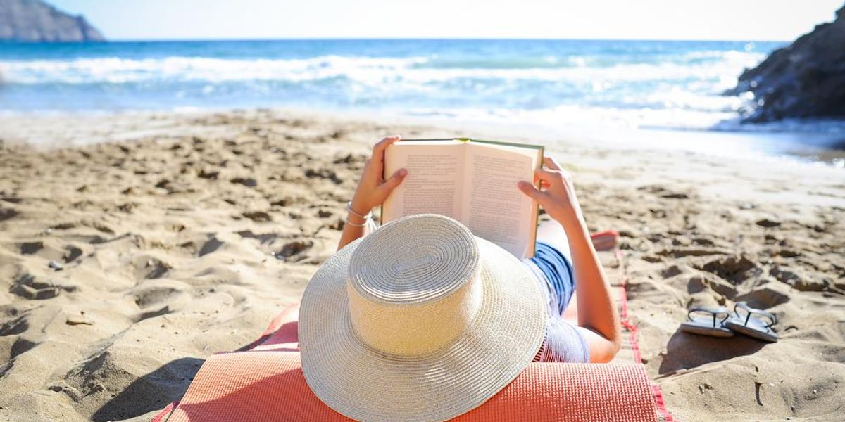Nő könyvet olvas a homokos tengerparton