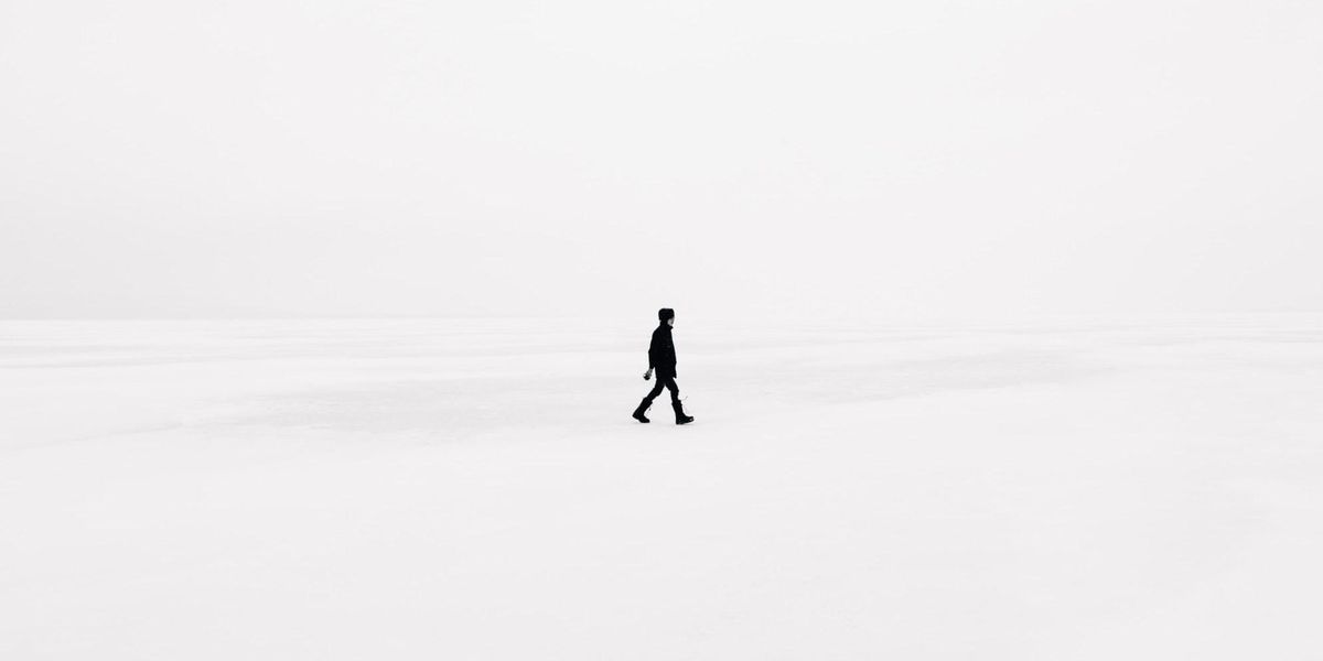 Fekete ruhás férfi fehér tájban sétál