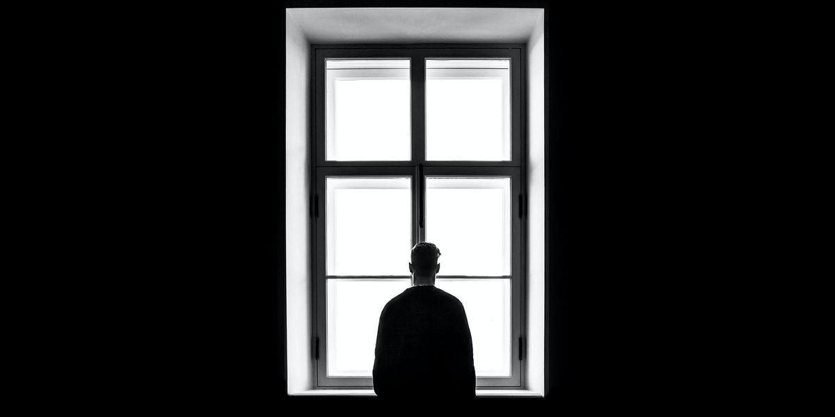 Ablakon kinéző férfi, sötét szobában