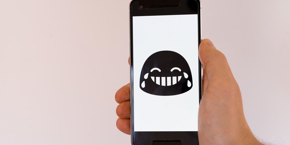 Sírva nevető emoji egy mobiltelefon képernyőjén