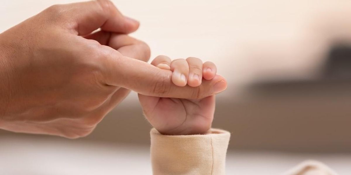 Egy kisbaba fogja az apukája ujját