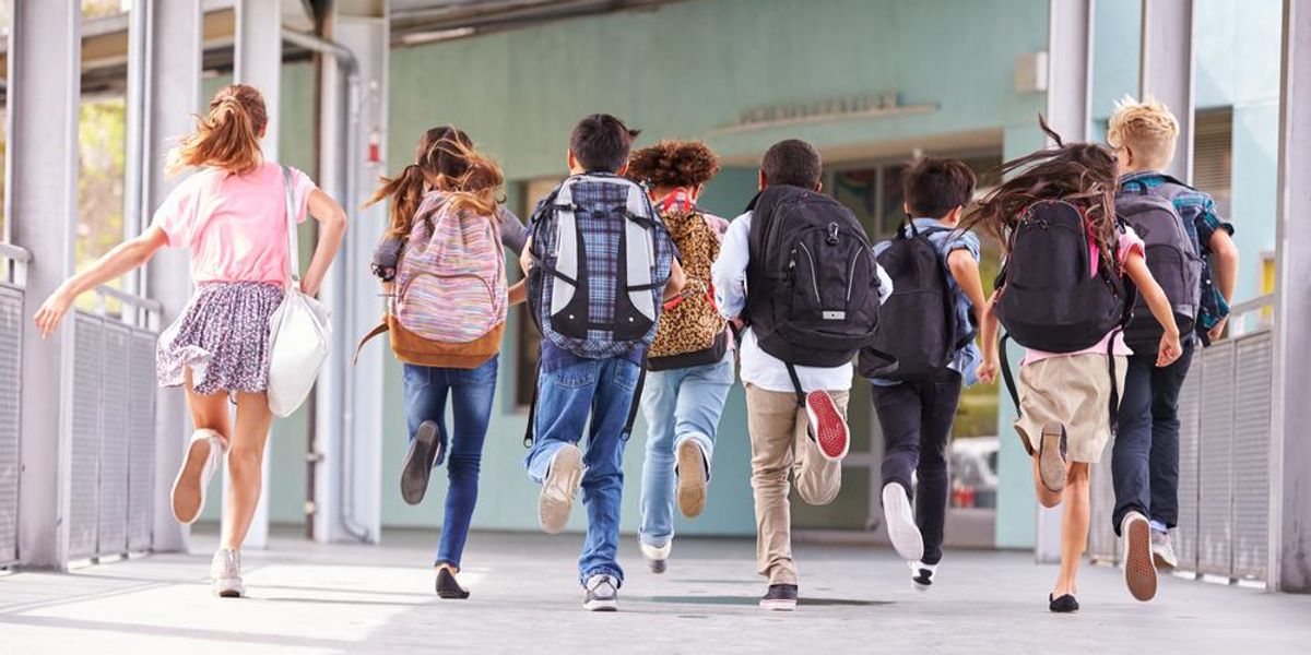 Általános iskolás gyerekek futnak az iskolába, hátulnézet