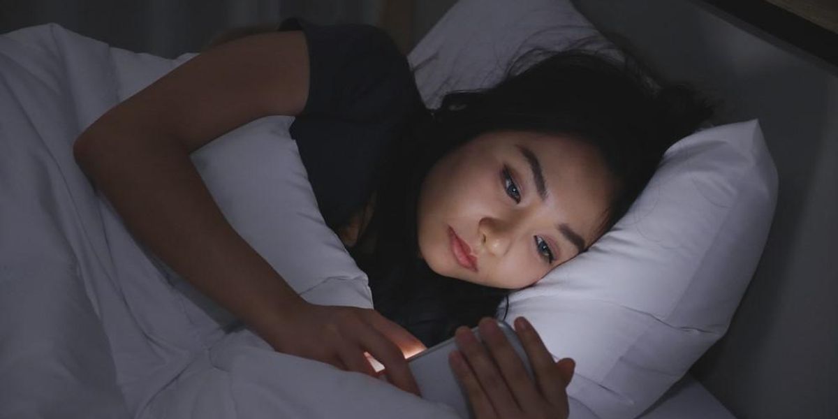 Egy lány telefonozik az ágyában fekve