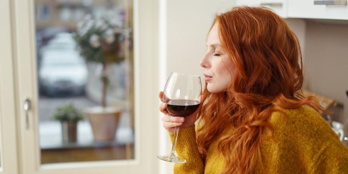 Egy sárga pulcsis nő vörösbort iszik