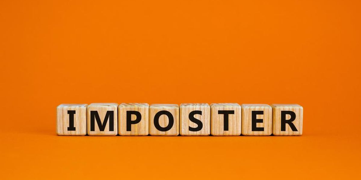 Fakockákon álló betűkből kirakott Imposztor(-szindróma) kifejezés narancssárga háttéren