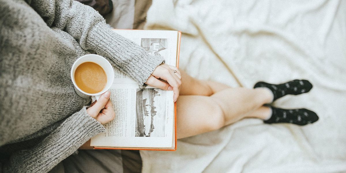 Egy lány egy csésze kávé mellett olvas