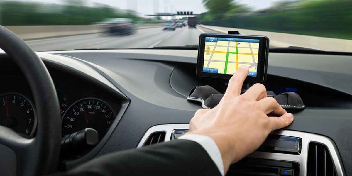 Egy ember a kocsijában lévő GPS-t állítja vezetés közben