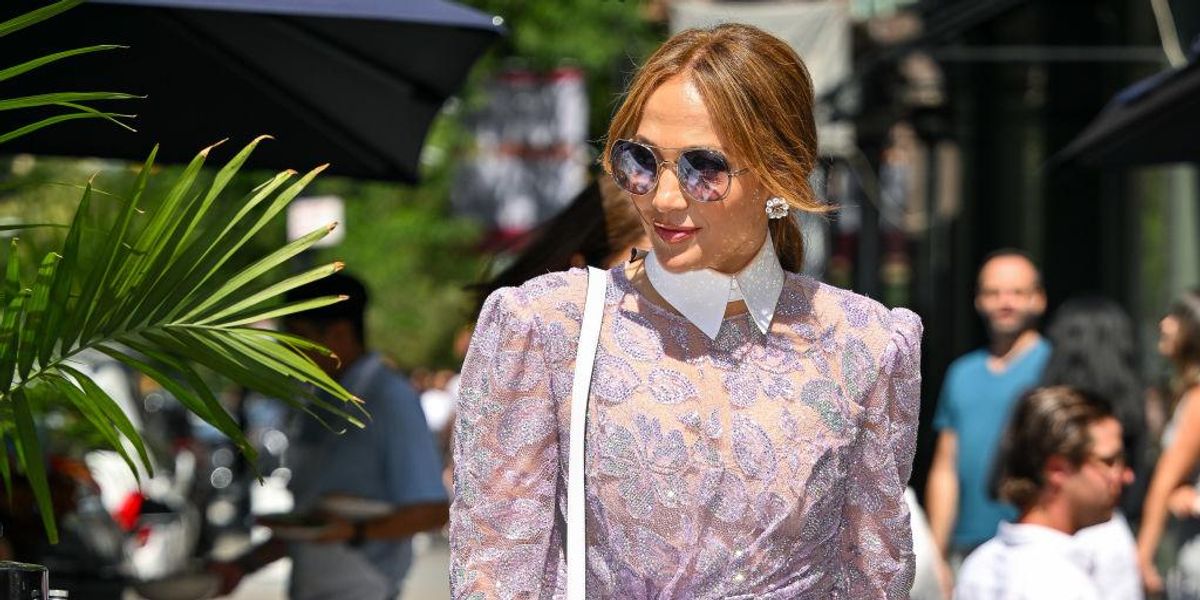 Jennifer Lopez napszemüvegben, lila ruhában sétál