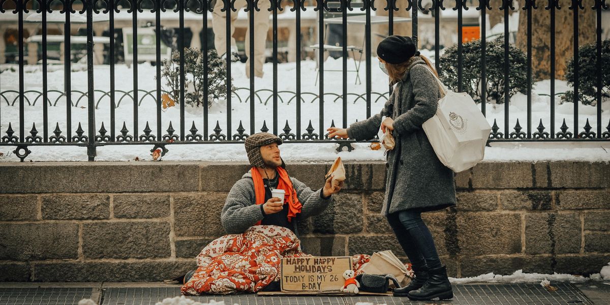 Egy járókelő kisegít egy földön ülő hajléktalant