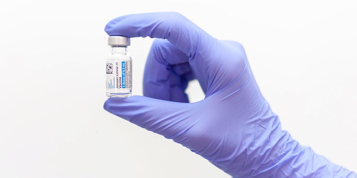 Egy gumikesztyűs ember koronavírus elleni vakcinát tart a kezében
