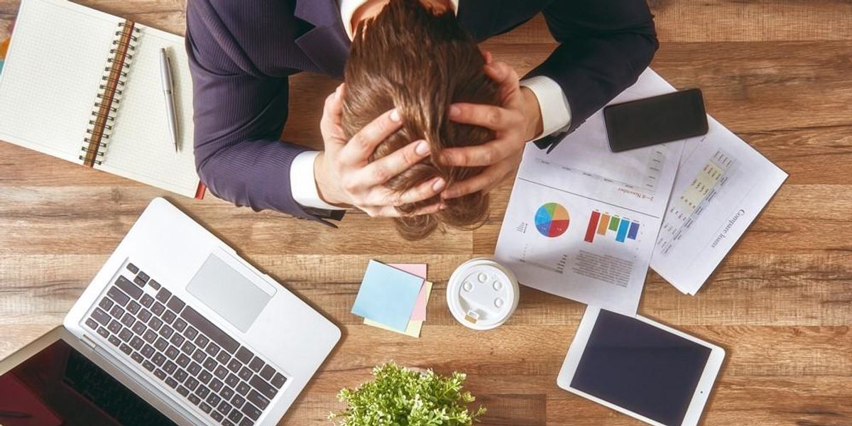 Egy férfi stressz miatt fogja a fejét a munkahelyén