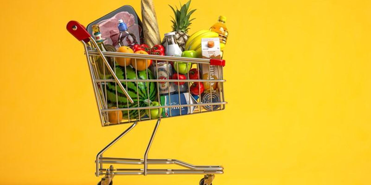 Bevásárlókocsi tele élelmiszerrel sárga háttér előtt