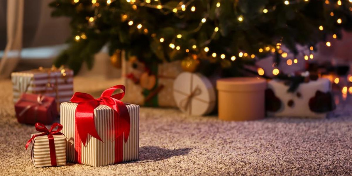 Karácsonyi ajándékok a földön, háttérben karácsonyfa 