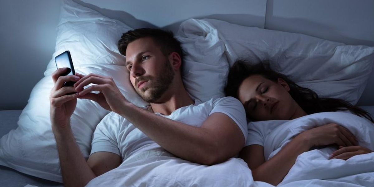 Egy férfi az alvó barátnője mellett telefonozik