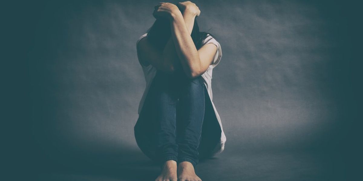 Fejét az ölébe hajtó nő - depresszió koncepció