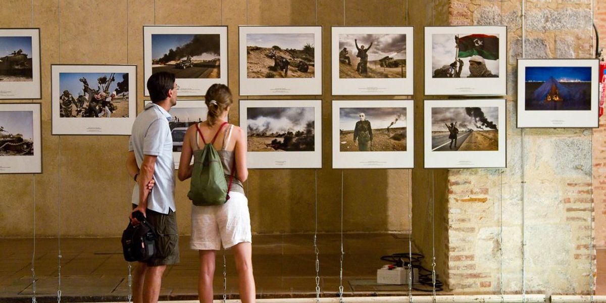 World Press Photo-kiállításon áll egy fiatal pár és a képeket nézik