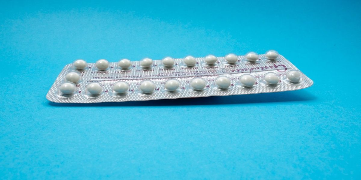 Szájon át szedhető fogamzásgátló tabletta kék háttéren
