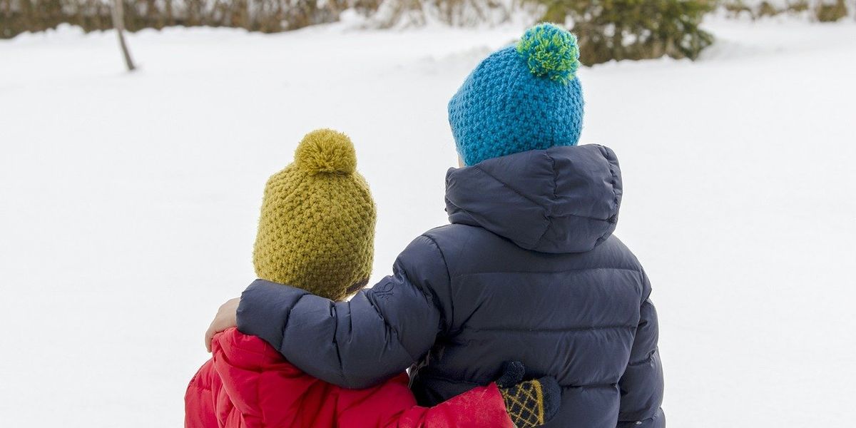 Két kisgyerek áll téli ruházatban a hóban