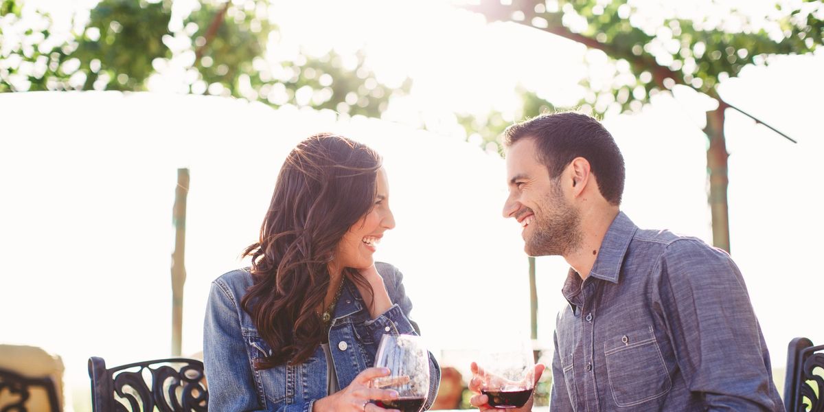 egy nő és egy férfi bort isznak és együtt nevetnek egy teraszon
