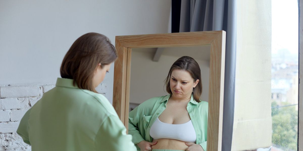 egy túlsúlyos nő a tükörben nézi magát