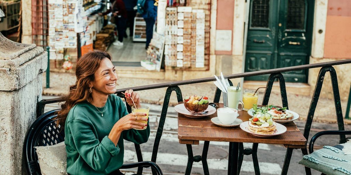 Lisszabonban limonádét egy turista lány, mellette ételekkel teli asztal