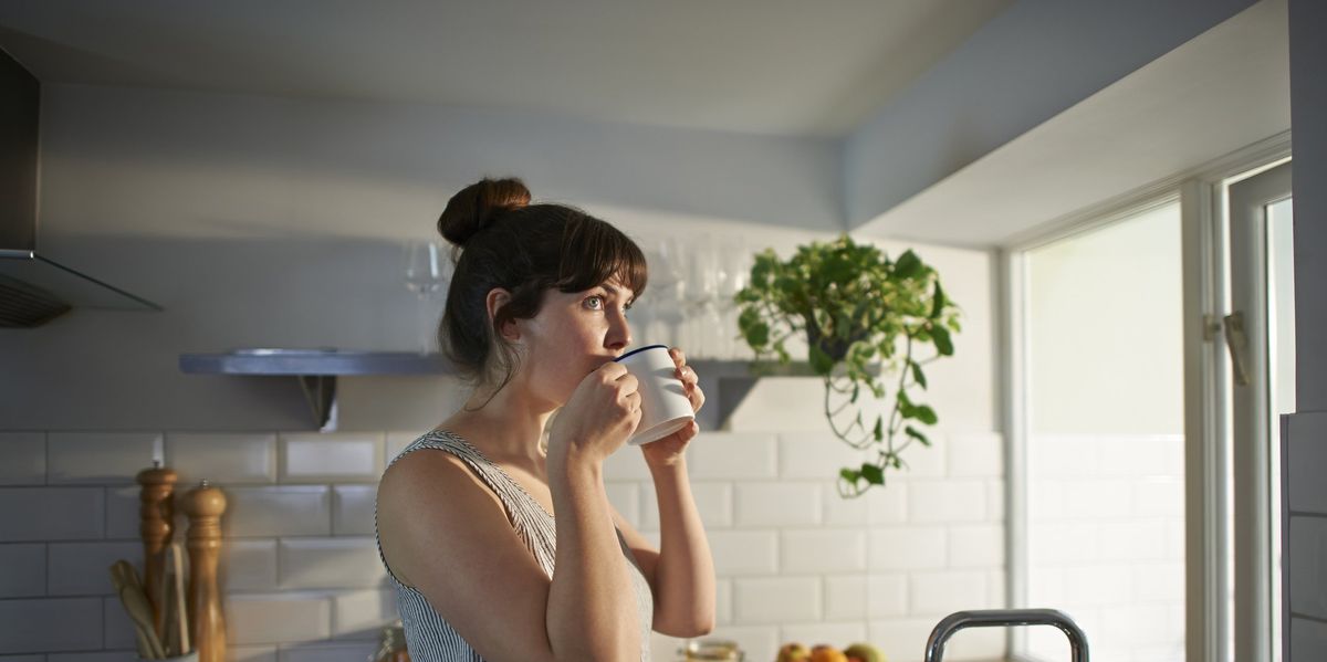 kávét iszik egy nő egy bögréből a konyhában