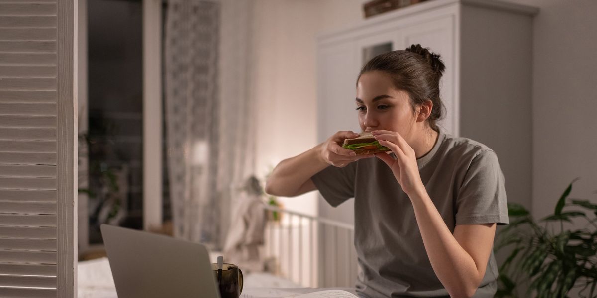 egy fiatal nő tanulás közben szendvicset eszik