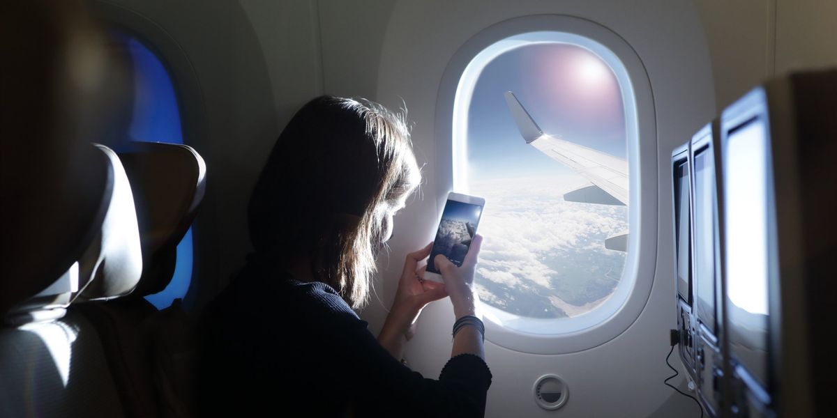 egy nő fényképet készít a repülőn a telefonjával