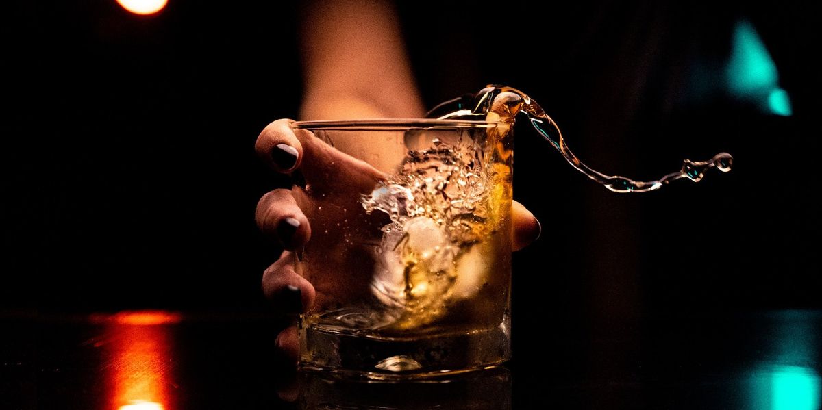 Alkohollal és jégkockákkal teli poharat tartó női kéz