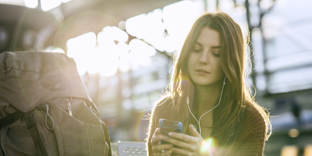 egy nő egyedül utazik és a telefonján épp zenét hallgat, mellette a hátizsákja