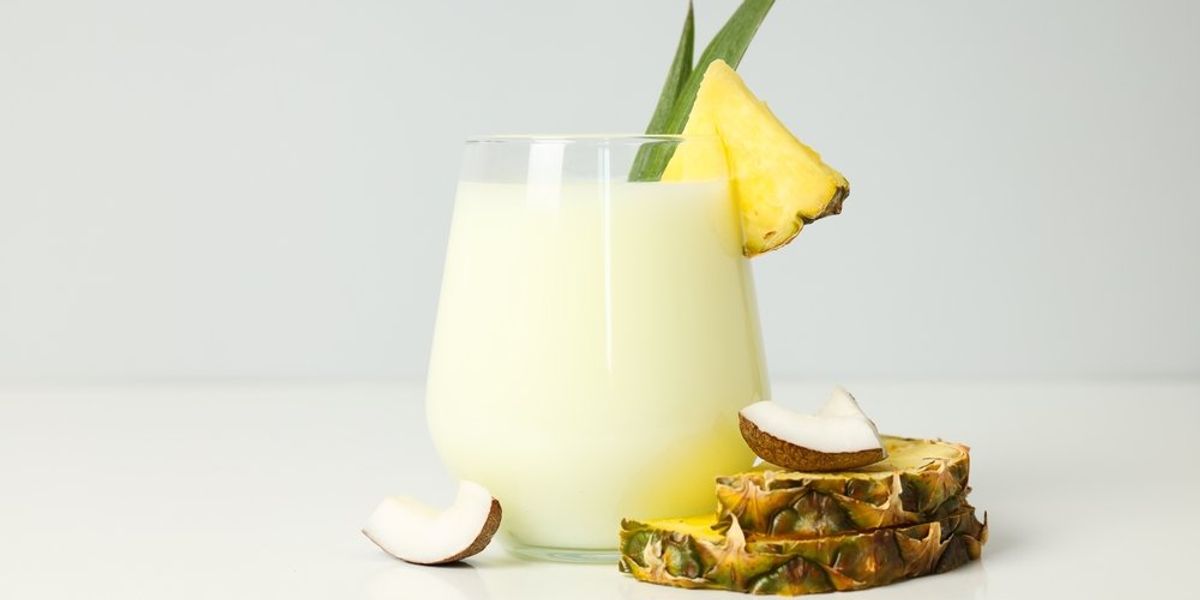 Piña colada koktél, mellette kókusz darabok és ananász szeletek