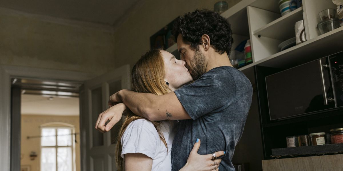 egy nő és egy férfi egymást átölelve csókolózik a konyhában