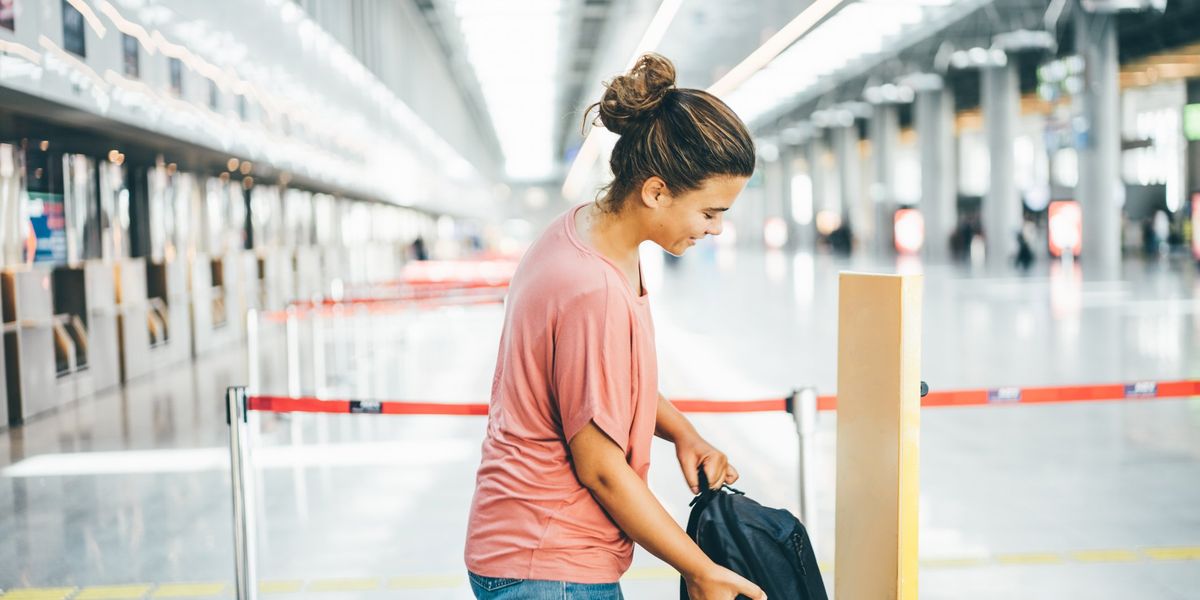 egy nő leméri a táskája méretét a repülőtéren