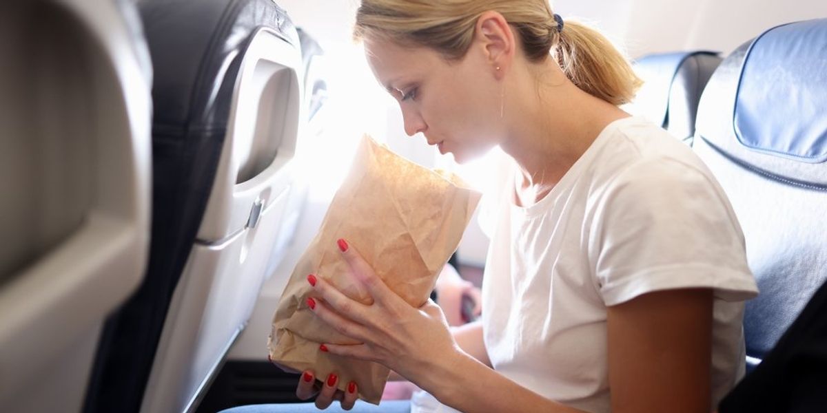 Repülőgépen rosszul lévő nő hányózacskót tart a kezében