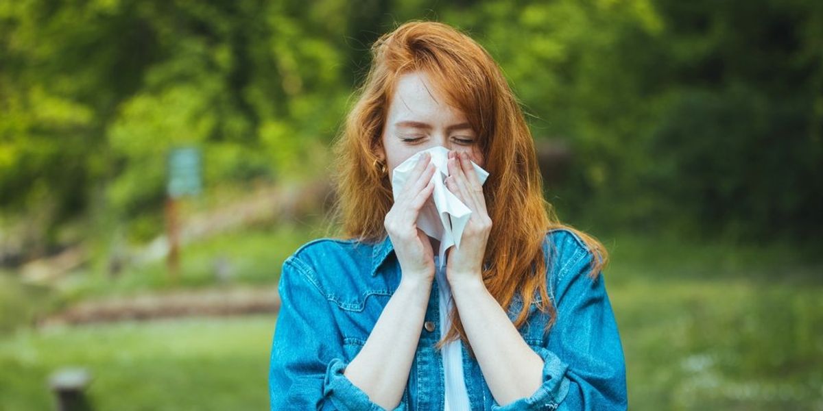 Orrát fújó nő a szabadban - allergia koncepció