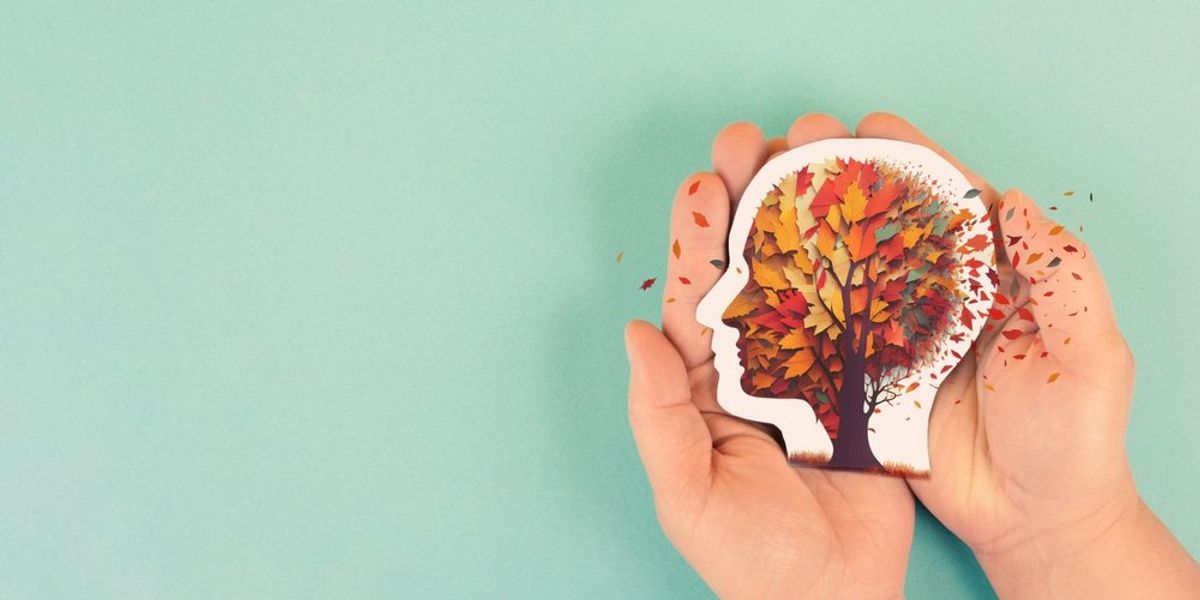 Alzheimer-kór, demencia - Fej alakú papírformát tartó kéz, ameéyből falevelek szállnak ki