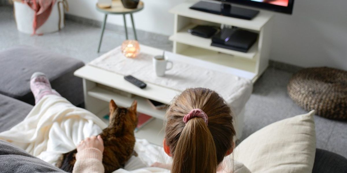 egy nő a cicájával nézi a tévét
