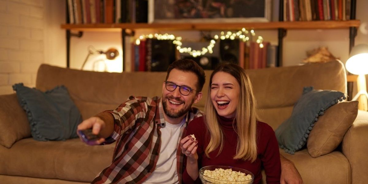 egy férfi és egy nő popcront eszik és közben tévét néz a nappaliban