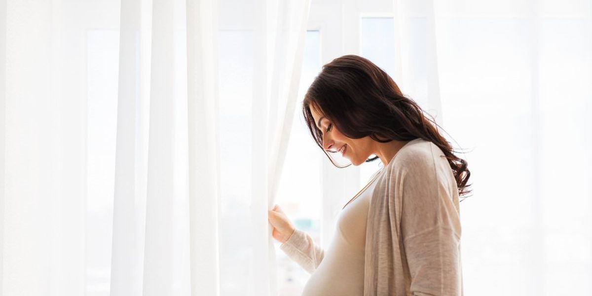egy várandós nő mosolyog a hasát fogva