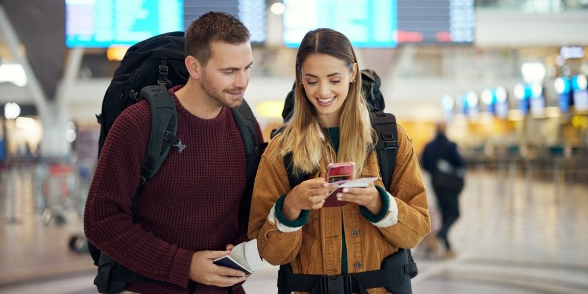 Repülőtéren álló pár nézi a nő mobilját
