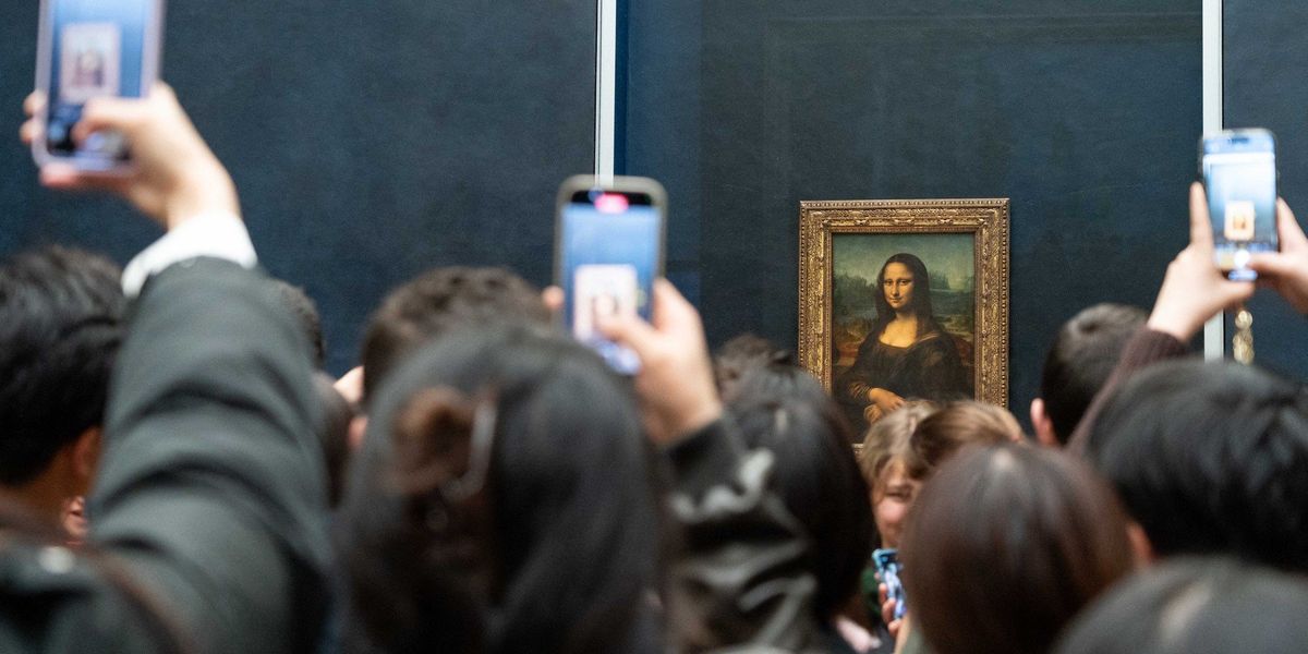 Látogatók fényképezik a Mona Lisa című festményt telefonjukkal a párizsi Louvre Múzeumban 2023. december 12-én