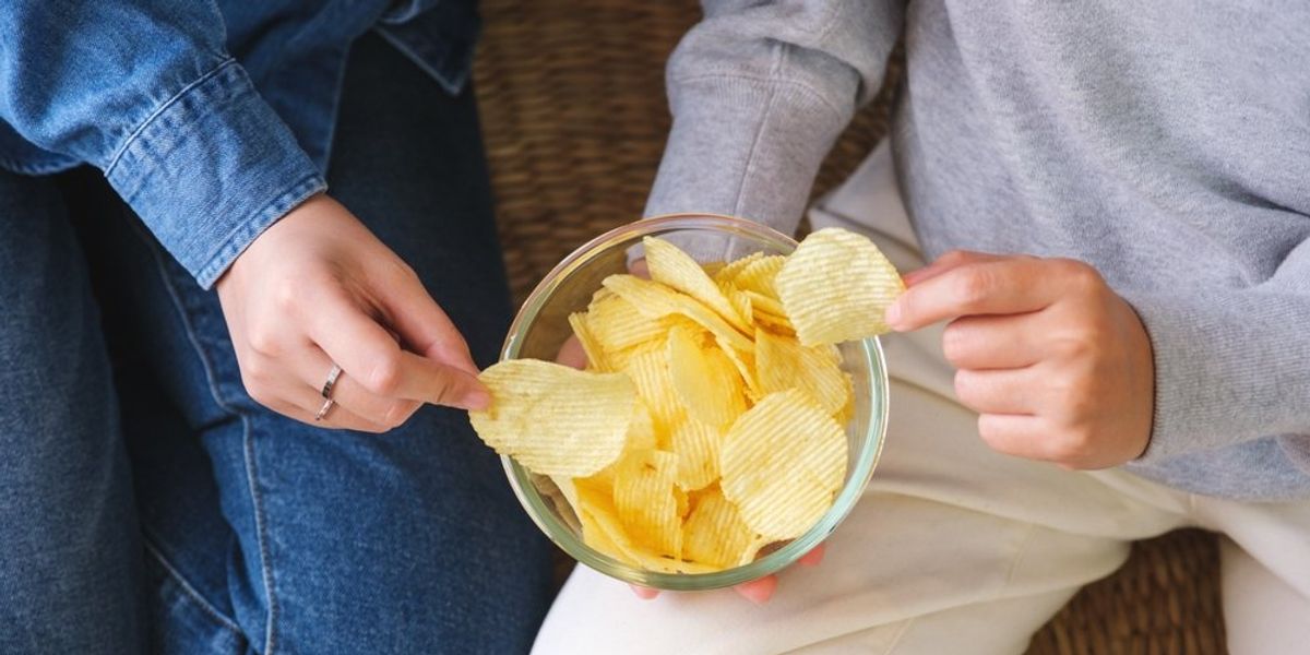 Tál chips-ből falatozó kezek